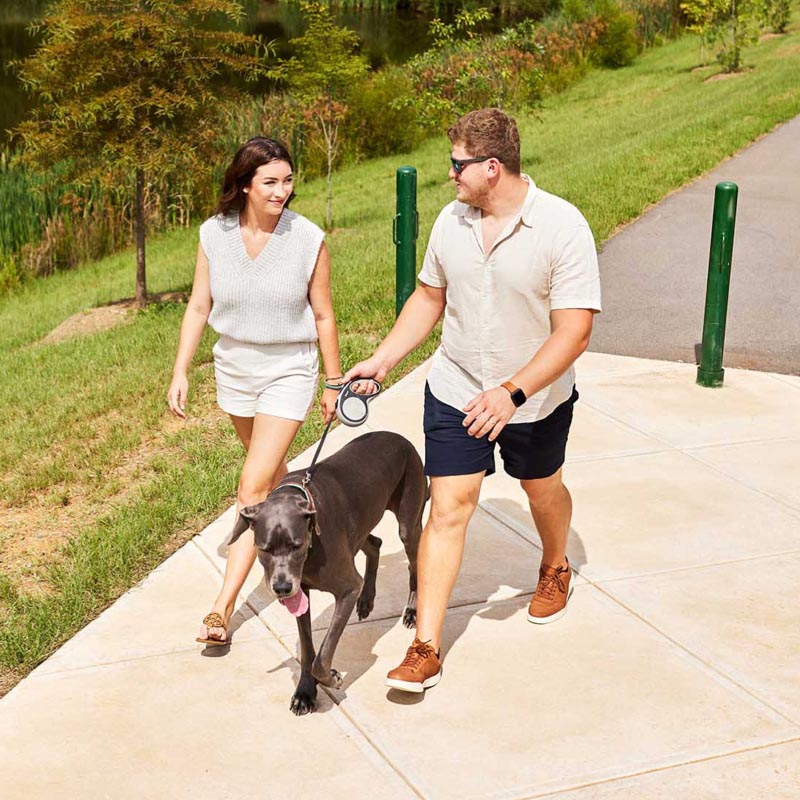 couple with dog go for walk on community trail